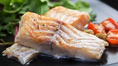 some fish and vegetables on a black plate