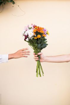 two people holding flowers in their hands