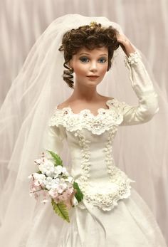 a doll wearing a wedding dress and veil with flowers in her hair is posed for the camera