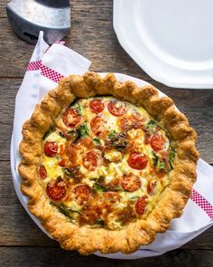 a quiche with tomatoes and spinach on a wooden table