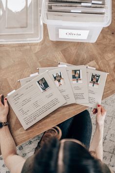 a woman sitting at a table with four photos in front of her on the floor