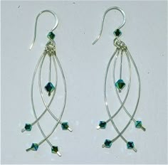 two pairs of silver earrings with swarong and crystal beads hanging from the ends