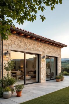 an outdoor patio area with potted plants and lights on the side of the house