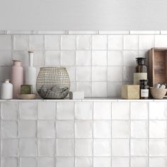 a shelf filled with different types of items on top of a white tiled wall in a kitchen