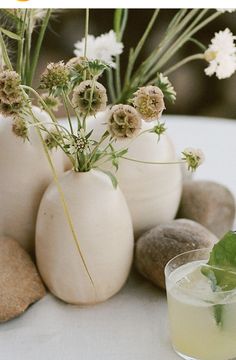 flowers in vases sitting next to rocks and a drink