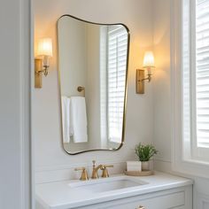 a bathroom sink with a large mirror above it and two lights on either side of the sink