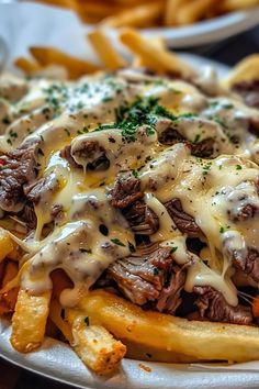 a white plate topped with french fries covered in cheese and steak sauce on top of it