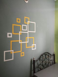 the wall is painted with yellow and white squares on it, along with a metal bed frame