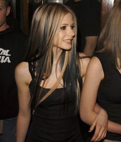 a woman with long hair standing in front of other people at a party or gathering