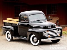 an old black truck parked in front of a building