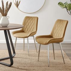 two chairs sitting on top of a rug next to a table with a vase and potted plant