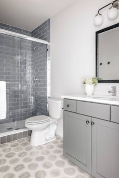 a white toilet sitting next to a bath tub in a bathroom under a large mirror