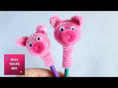 two pink crocheted pigs with eyes sticking out of them's ends, in front of a white background