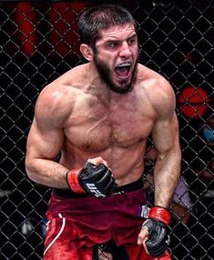 a shirtless man with his mouth open and boxing gloves on, standing in front of a chain link fence