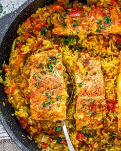 fish and rice in a skillet with a spoon on the side, ready to be eaten