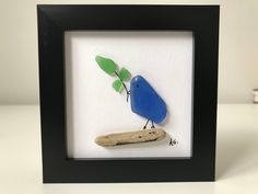 a blue bird sitting on top of a piece of wood next to a green leaf