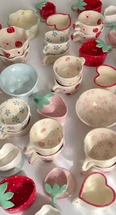 a table topped with lots of different bowls and plates covered in strawberry print design on them