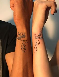 two people holding hands with tattoos on their arms, one has a crown and the other has a heart