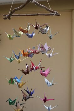 an origami bird mobile hanging from a tree branch in front of a door