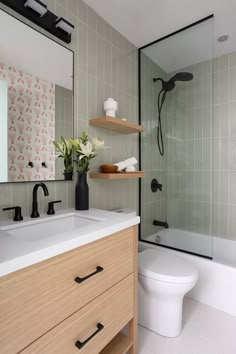 a white toilet sitting under a bathroom mirror next to a sink and a bath tub