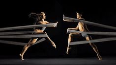 two women are dancing in the dark with their arms stretched out and legs spread wide