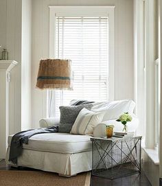 a living room with white furniture and pillows on the couch in front of a window