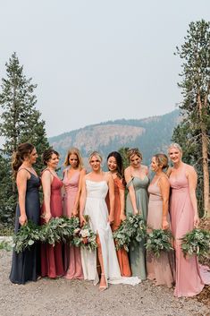 Seven bridesmaids in multicolored dresses stand around a bride in a modern dress against a mountain background. Eucalyptus Bouquets, August Wedding Colors, Mismatched Bridesmaids Dresses, Fall Mountain Wedding, Mix Match Bridesmaids, Fall Wedding Color Palette, Wedding Parties Colors, Modern Wedding Venue