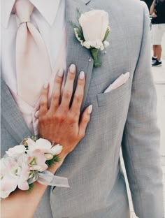 a close up of a person wearing a suit and tie with flowers on his lapel