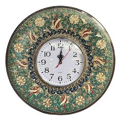 a clock that is on the side of a wall with flowers and leaves painted on it