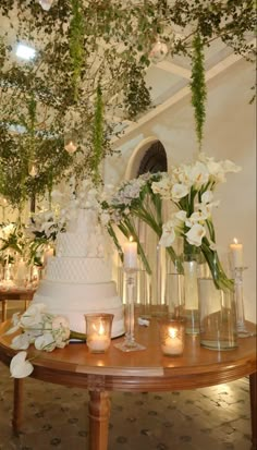 a wedding cake sitting on top of a table surrounded by vases and candle holders