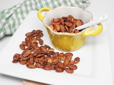 some nuts are in a yellow bowl and on a white plate