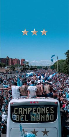 a group of people sitting on top of a bus in front of a large crowd