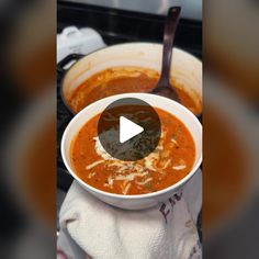 a white bowl filled with soup next to a silver spoon and napkin on top of a stove