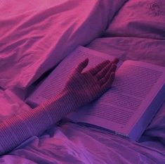 a person is laying in bed with their hand on an open book and wearing gloves