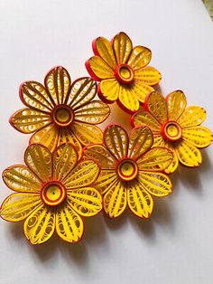 four yellow and red flower brooches sitting on top of a table