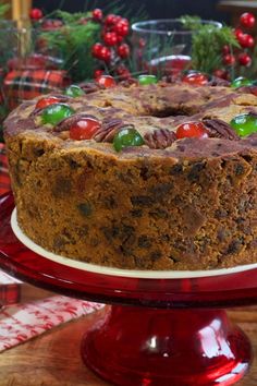 A white fruitcake with pecans and red and green cherries on top, sitting on a red cake stand. Pecans Candied, Candied Cherries, Tube Cake Pan, Candied Pineapple, Fresh Cake, Store Bought Cake