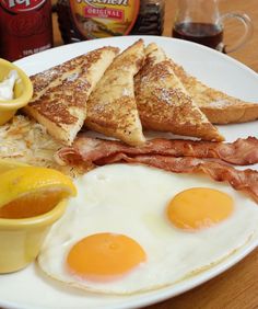 a plate with eggs, toast, and bacon on it next to ketchup