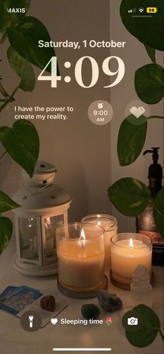 candles are sitting on a table next to a potted plant and an alarm clock