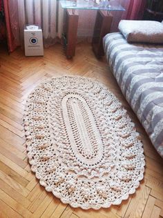 a crocheted doily on the floor next to a bed