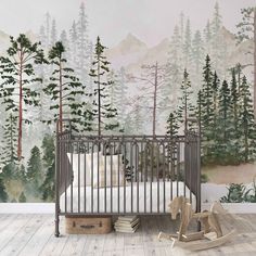 a baby crib in front of a forest mural