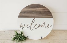 a wooden sign with the word welcome on it next to a small potted plant