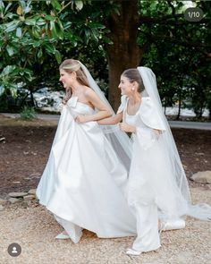 two women in white dresses and veils walking together