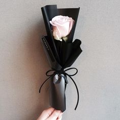 a hand is holding a black and white paper flower with the words welcome sweet february written on it