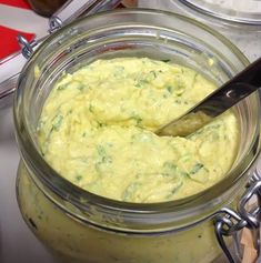 a spoon in a glass jar filled with yellow sauce on top of a countertop