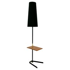 a lamp that is on top of a wooden table with a black shade over it