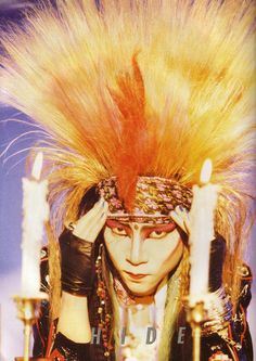 a woman with her hair in the shape of a headdress and some candles