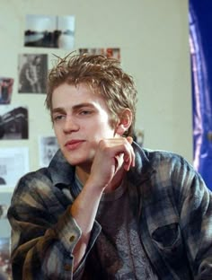 a young man sitting at a table with his hand on his chin and looking off to the side