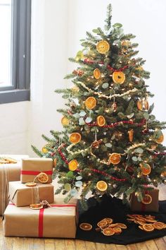 a small christmas tree is decorated with oranges and gold ornaments, along with presents