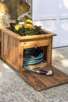 a planter box with flowers in it and a hose connected to the ground below