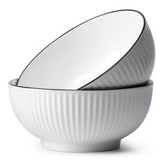 two white bowls with black rims are stacked on each other in front of one another